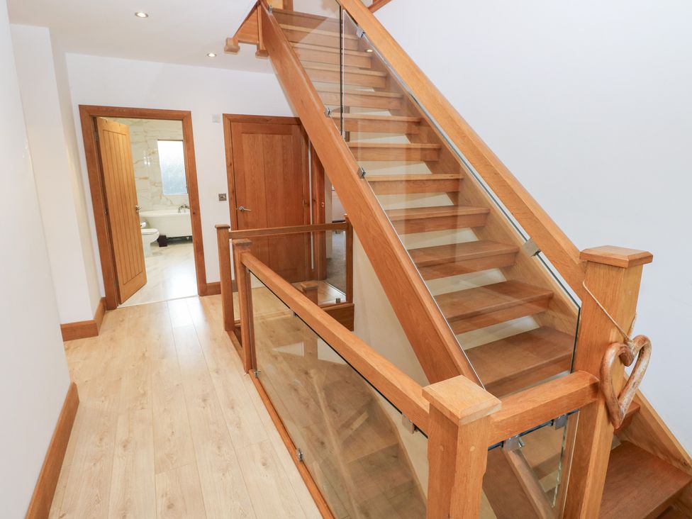A staircase with wooden handrail and door leading to a bathroom at Ty-Gan Dderwen in Llanelli
