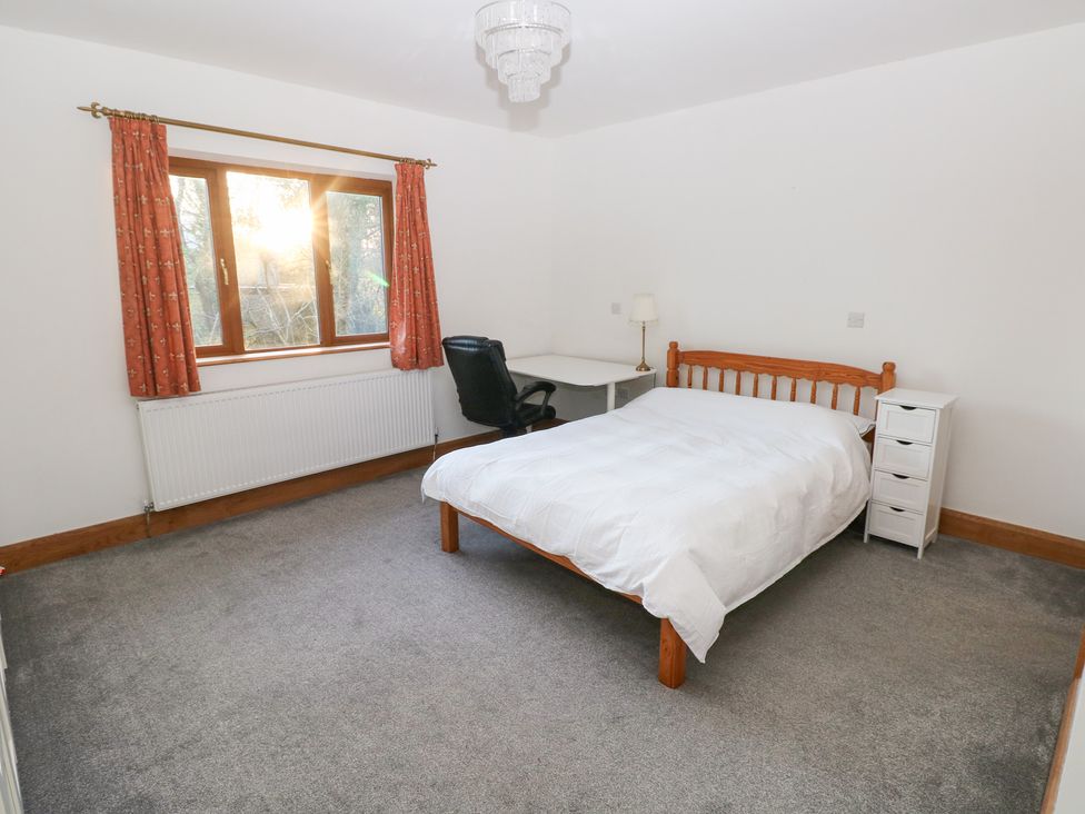 A bedroom with a bed, desk, chair, and drawer unit at Ty-Gan Dderwen in Llanelli