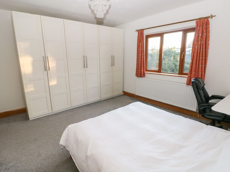 A bedroom with a wardrobe and a desk at Ty-Gan Dderwen in Llanelli