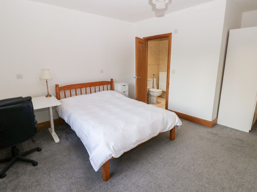 A bedroom with a bed, desk, chair, and wardrobe at Ty-Gan Dderwen Llanelli