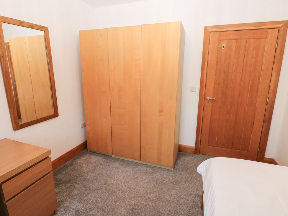 A bedroom with a wardrobe, mirror, and drawers at Ty-Gan Dderwen in Llanelli