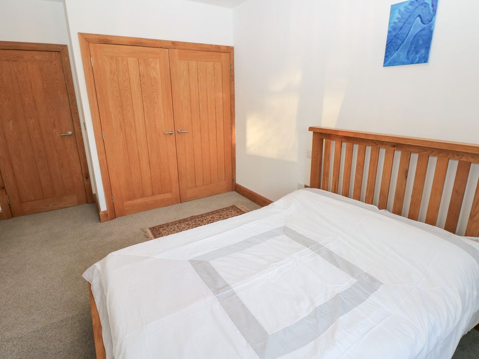 A bedroom with a bed and doors at Ty-Gan Dderwen in Llanelli