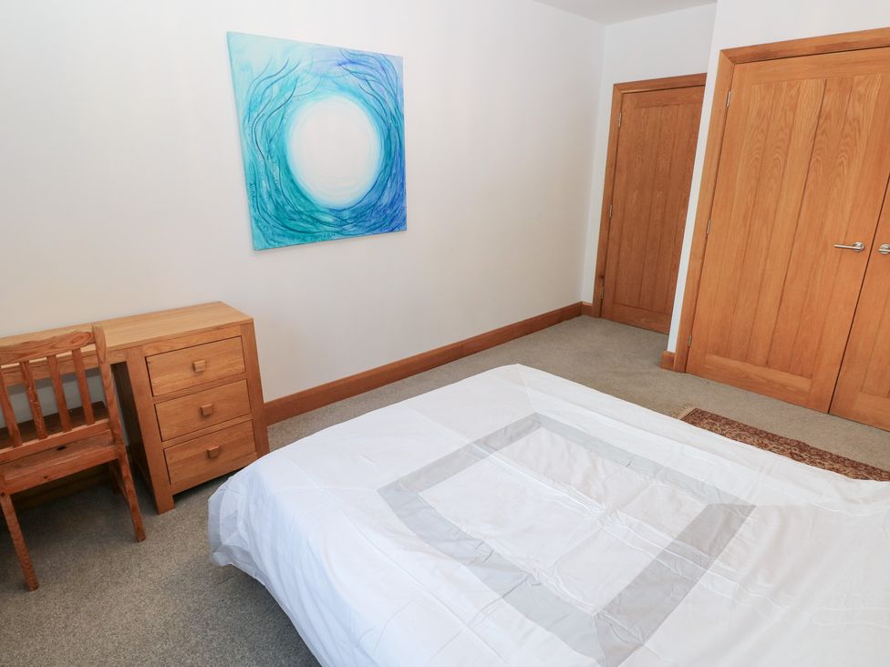A bedroom with a bed, chair, and drawer at Ty-Gan Dderwen in Llanelli