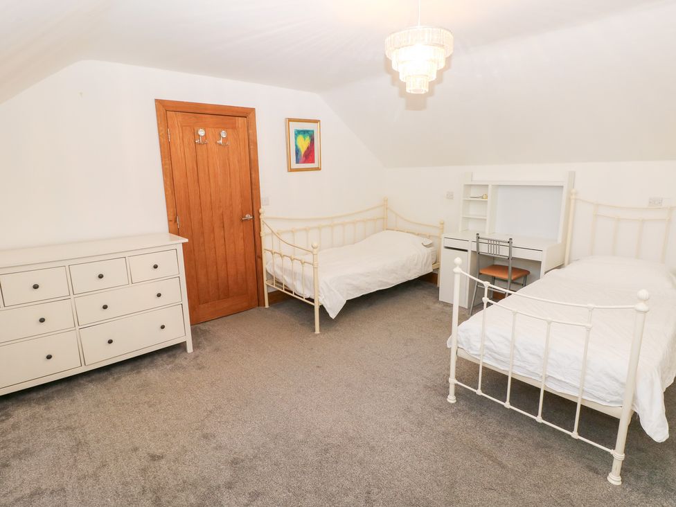 A bedroom with two beds and a dresser at Ty-Gan Dderwen in Llanelli