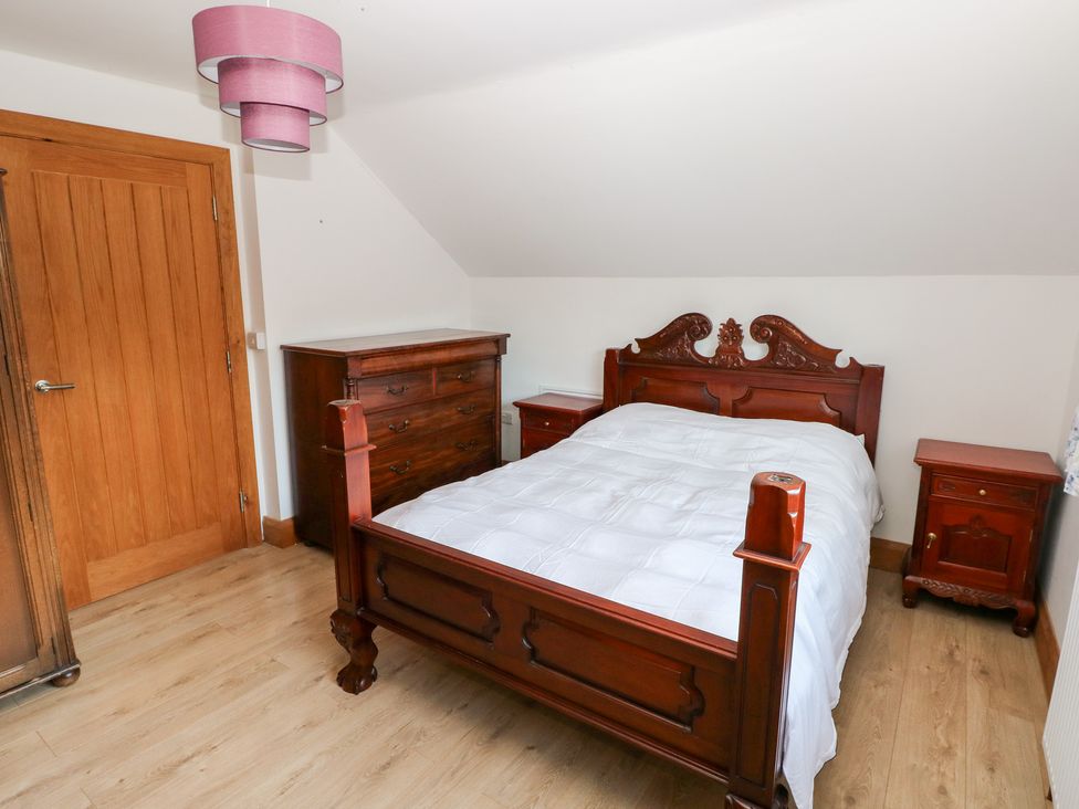 A bedroom with a wooden bed and furniture at Ty-Gan Dderwen in Llanelli