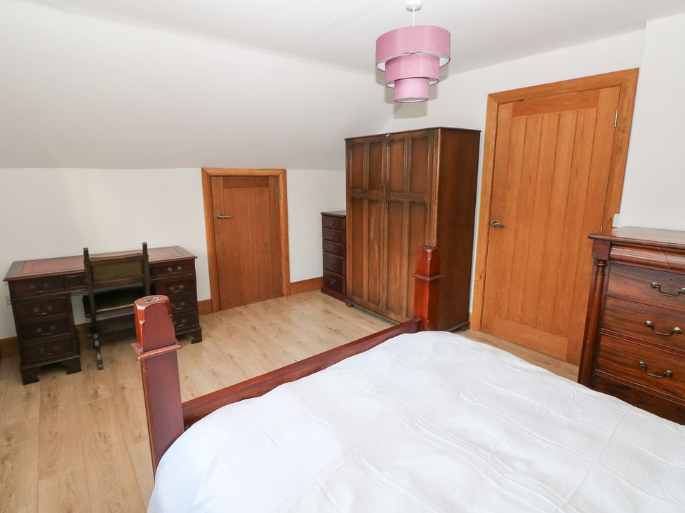 A bedroom with a bed, desk, and wardrobe at Ty-Gan Dderwen in Llanelli