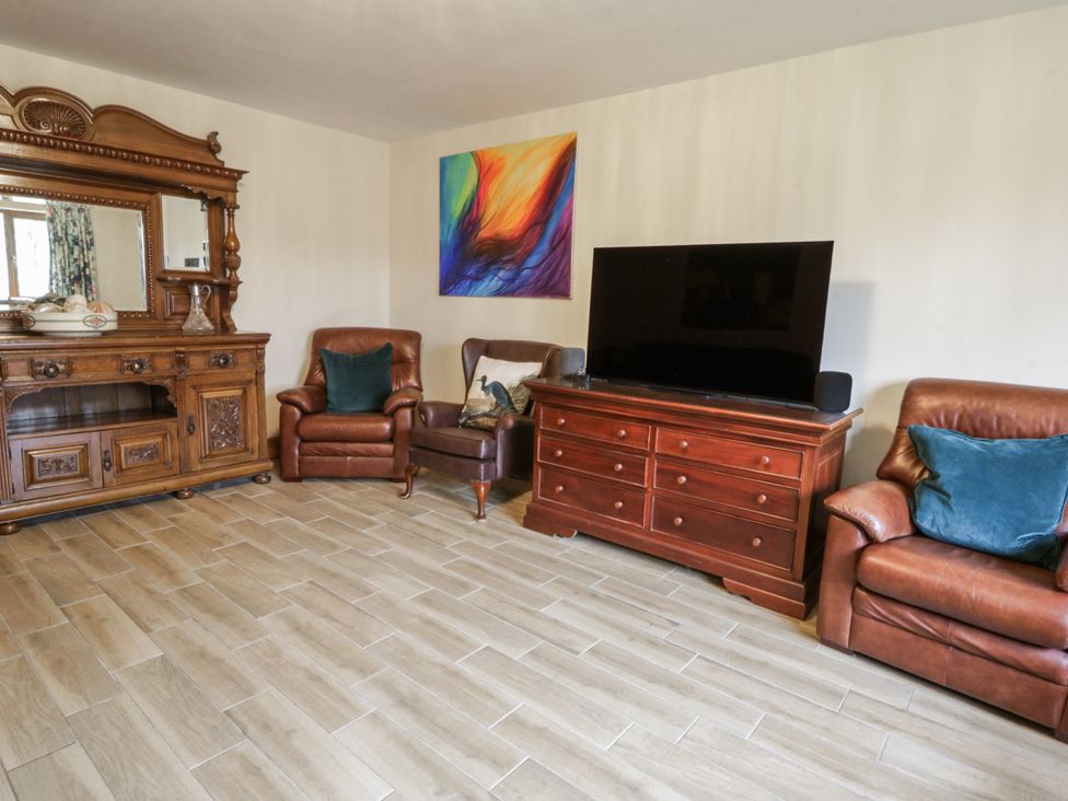 A living room with a television and seating arrangements at Ty-Gan Dderwen Llangennech