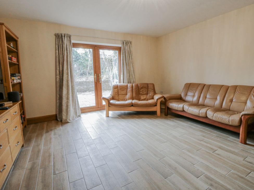 A living room with a sofa and wooden door at Ty-Gan Dderwen in Llangennech