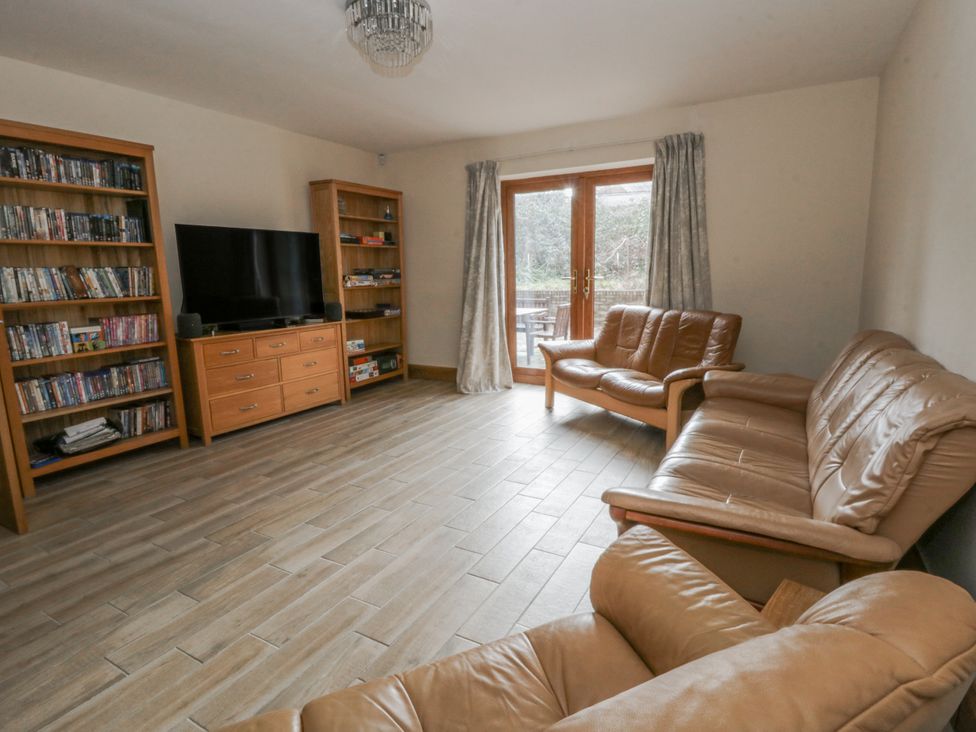 A living room with a television and bookshelves at Ty-Gan Dderwen in Llangennech