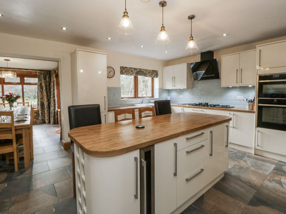 A kitchen with an island and stools at Ty-Gan Dderwen in Llangennech