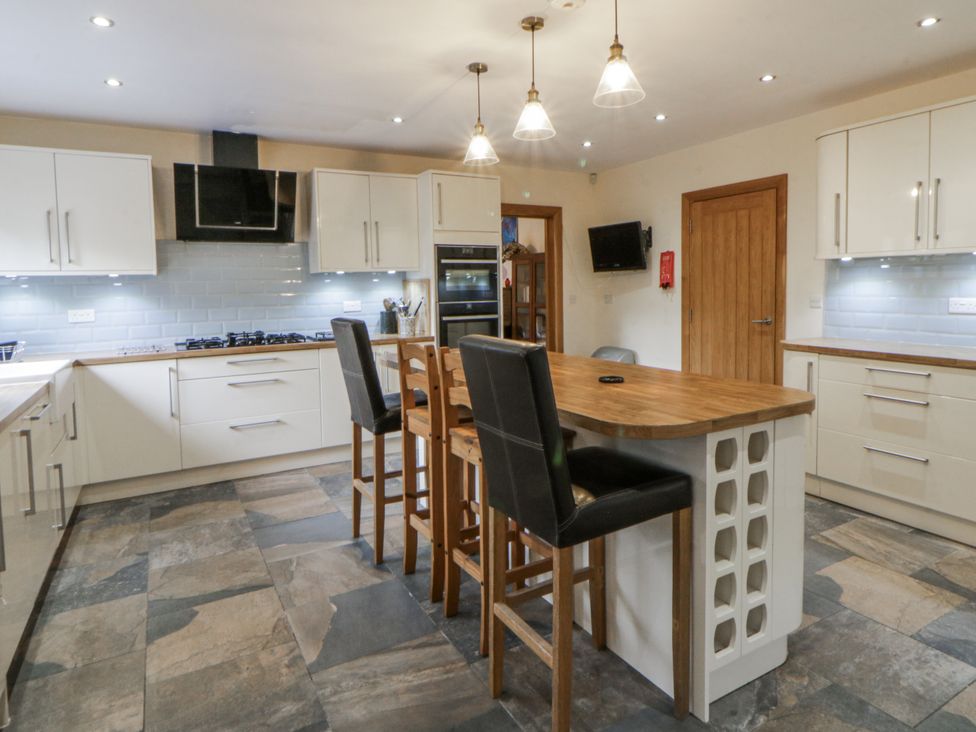 A kitchen with island and bar stools at Ty-Gan Dderwen in Llangennech