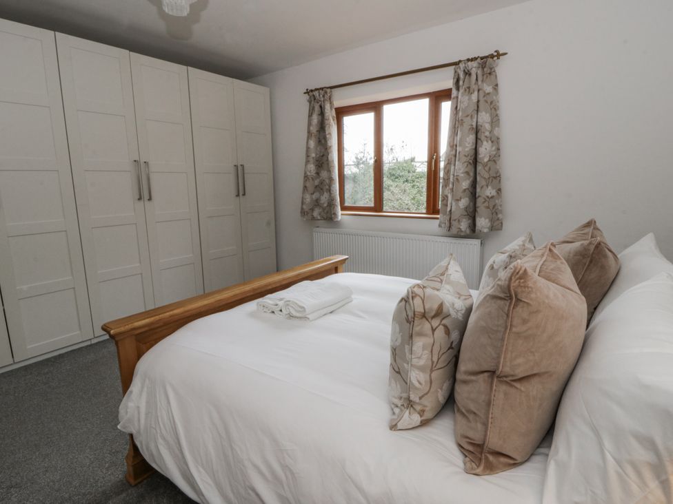 A bedroom with a bed and wardrobe at Ty-Gan Dderwen in Llangennech