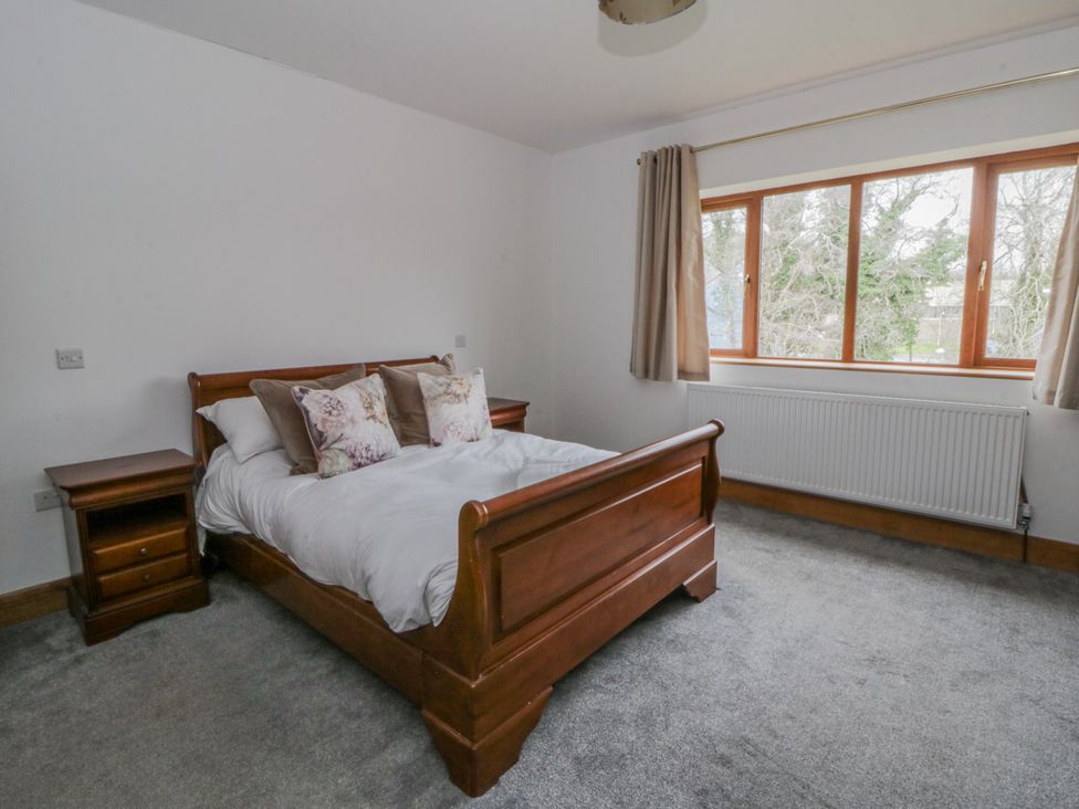 A bedroom with a bed and a nightstand at Ty-Gan Dderwen in Llangennech