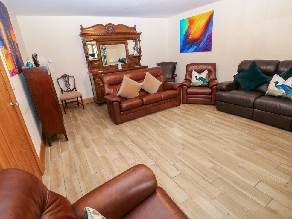 A living room with brown sofas and an ornate mirror at Ty-Gan Dderwen in Llangennech, Llanelli