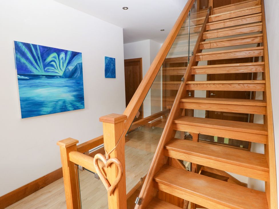 A staircase in a hallway with blue artwork at Ty-Gan Dderwen Llangennech, Llanelli