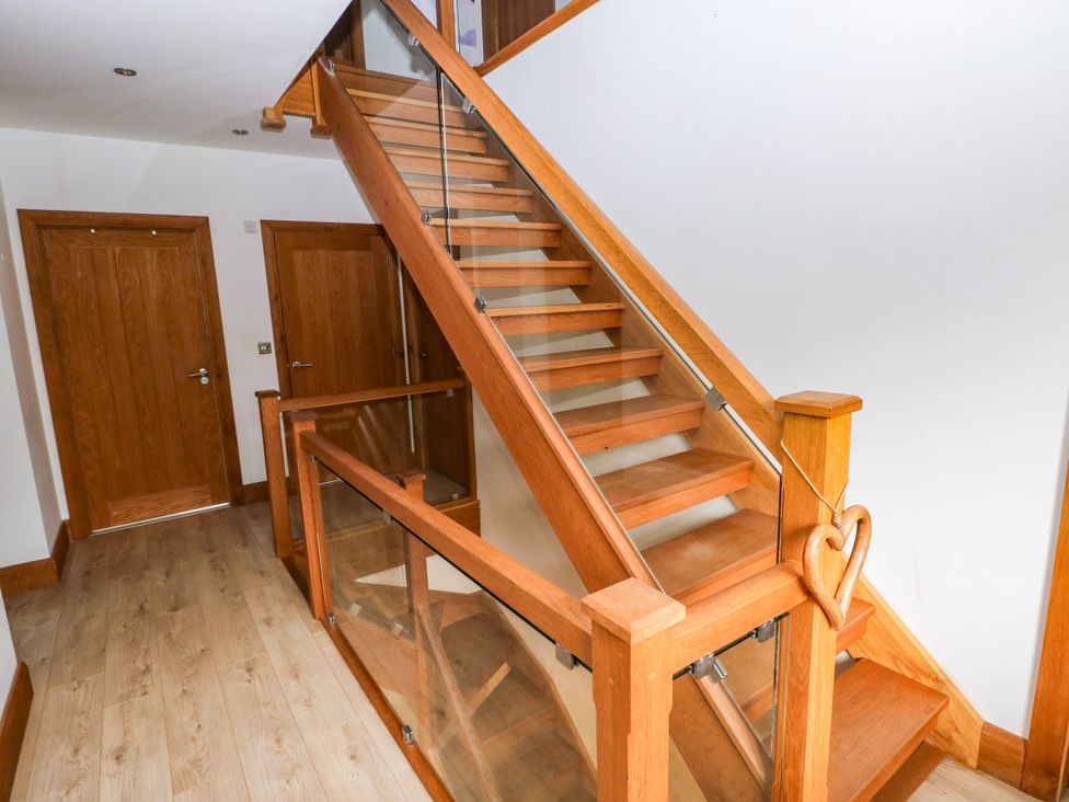 A staircase with wooden steps and railing in the hallway at Ty-Gan Dderwen in Llangennech, Llanelli