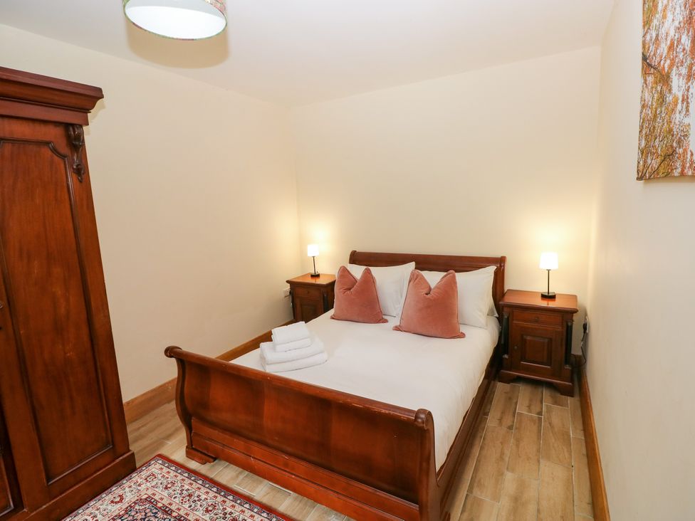 A bedroom with a bed and nightstands at Ty-Gan Dderwen in Llangennech, Llanelli