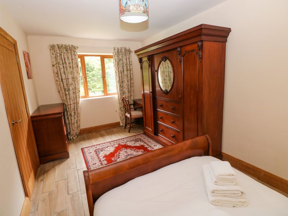 A bedroom with a bed, wardrobe, and dressing table at Ty-Gan Dderwen, Llangennech, Llanelli