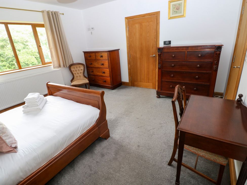 A bedroom with a bed, dresser and chest of drawers at Ty-Gan Dderwen, Llangennech, Llanelli