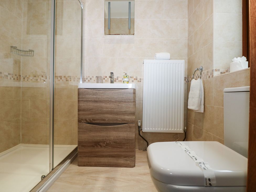 A bathroom featuring a sink, shower, toilet and radiator at Ty-Gan Dderwen in Llangennech, Llanelli