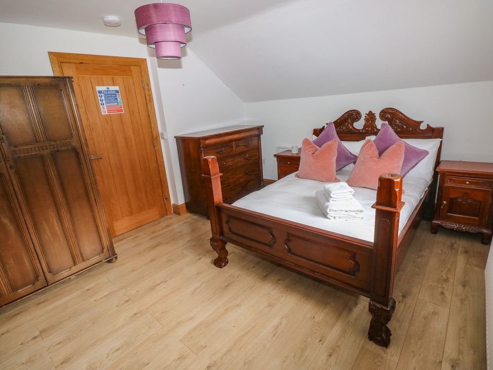 A bedroom with a wooden bed and wardrobe at Ty-Gan Dderwen in Llangennech, Llanelli