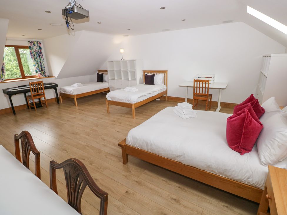 A bedroom with multiple beds and a desk at Ty-Gan Dderwen Llangennech, Llanelli