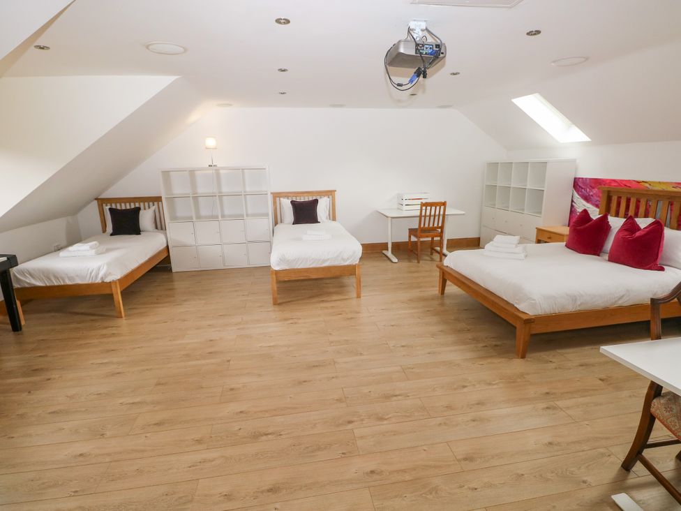 A bedroom with three beds and a shelf unit at Ty-Gan Dderwen in Llangennech, Llanelli