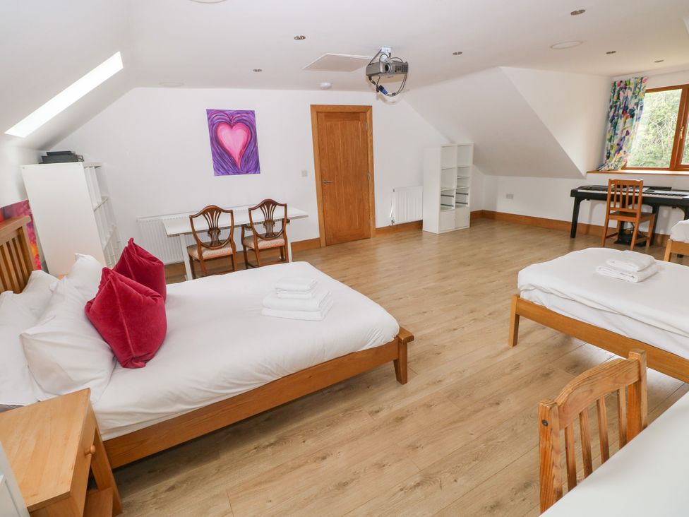 A bedroom with two beds and a table at Ty-Gan Dderwen in Llangennech, Llanelli