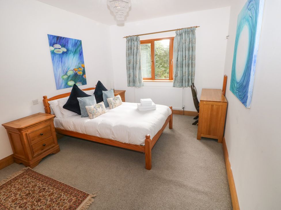 A bedroom with a bed and nightstand at Ty-Gan Dderwen, Llangennech, Llanelli