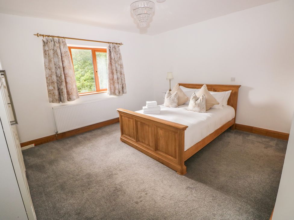 A bedroom with a double bed and window at Ty-Gan Dderwen in Llangennech, Llanelli