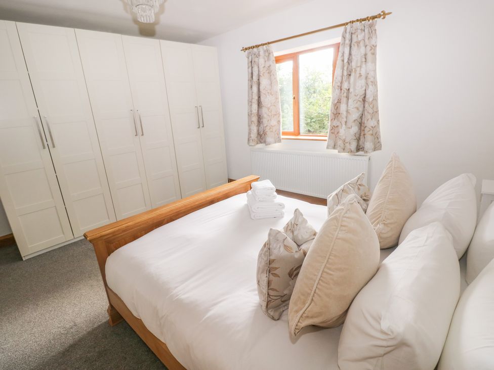 A bedroom with a bed and wardrobe at Ty-Gan Dderwen Llangennech, Llanelli