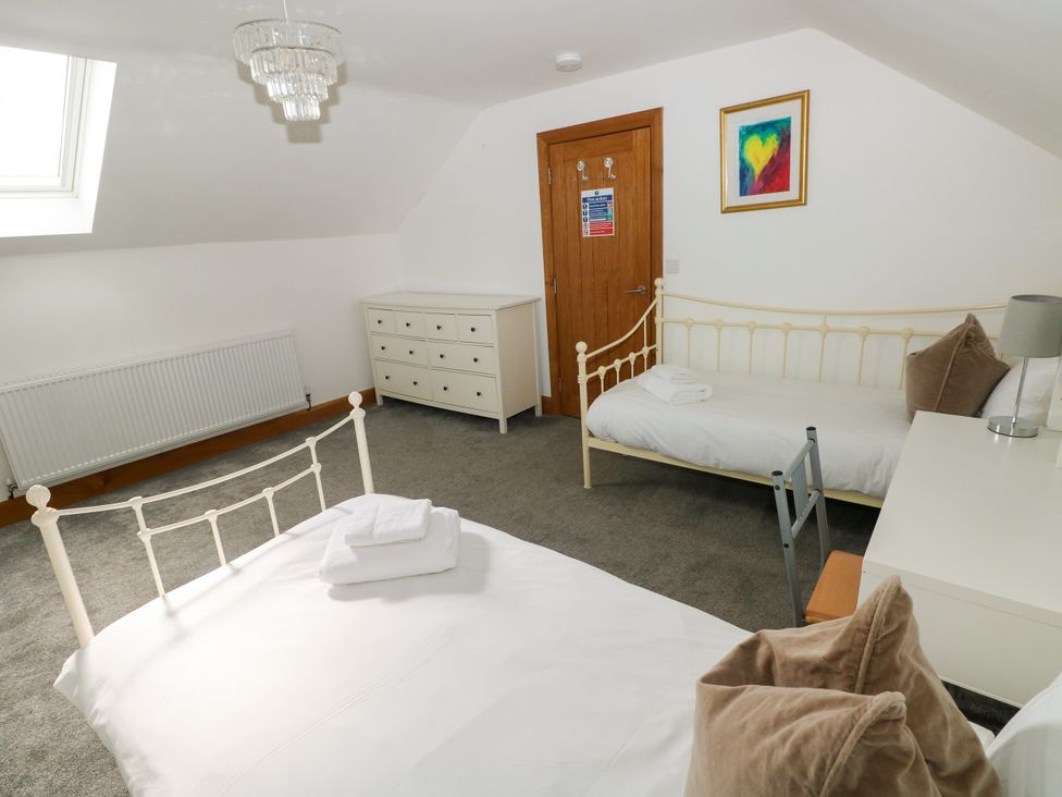 A bedroom with two beds, a chest of drawers and a window at Ty-Gan Dderwen, Llangennech, Llanelli
