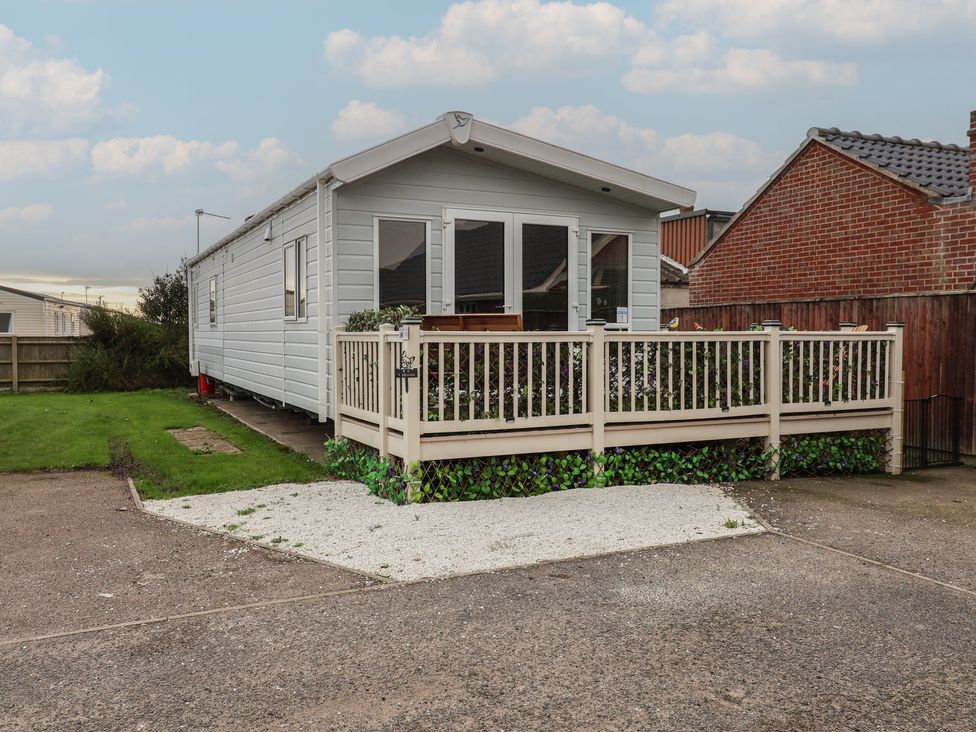A mobile home with a deck and grass area at Offspray Court 1 in Scratby