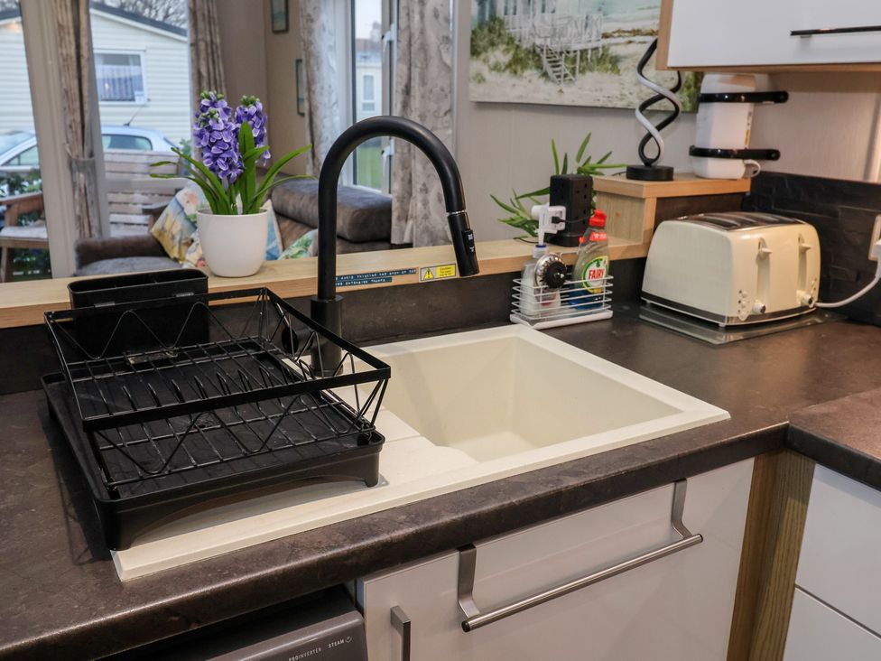 A kitchen with a sink and dish rack at Offspray Court 1 Scratby