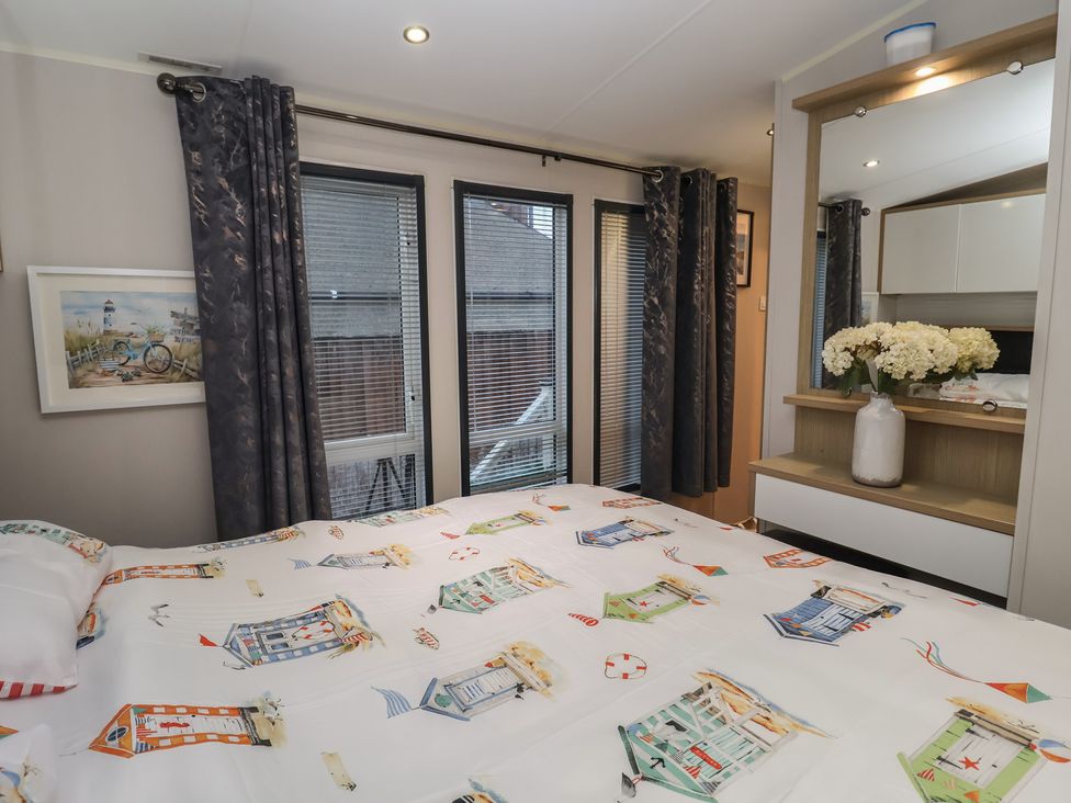 A bedroom with a bed and windows at Offspray Court 1 in Scratby