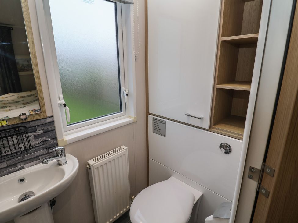 A bathroom with a toilet and sink at Offspray Court 1 Scratby