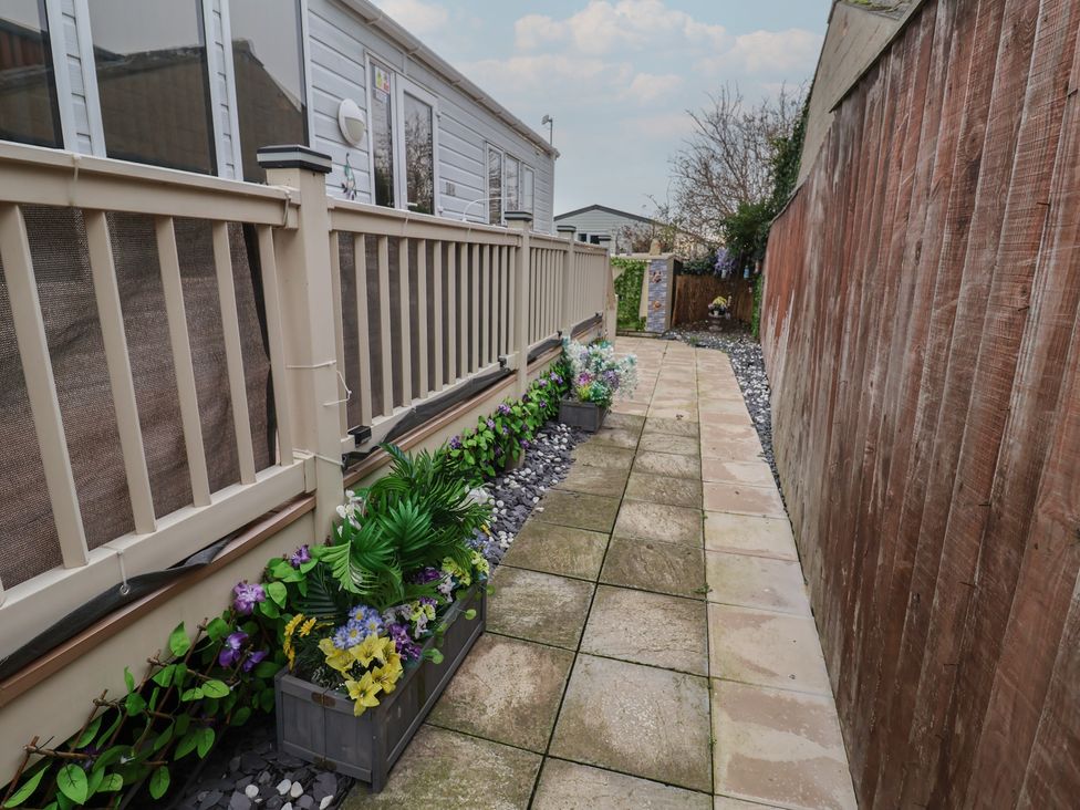 A garden path with planters and a fence at Offspray Court 1 Scratby