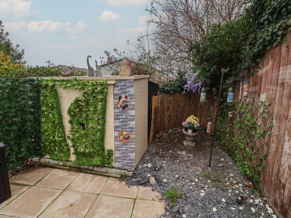 A garden with a shed and planters at Offspray Court 1 Scratby