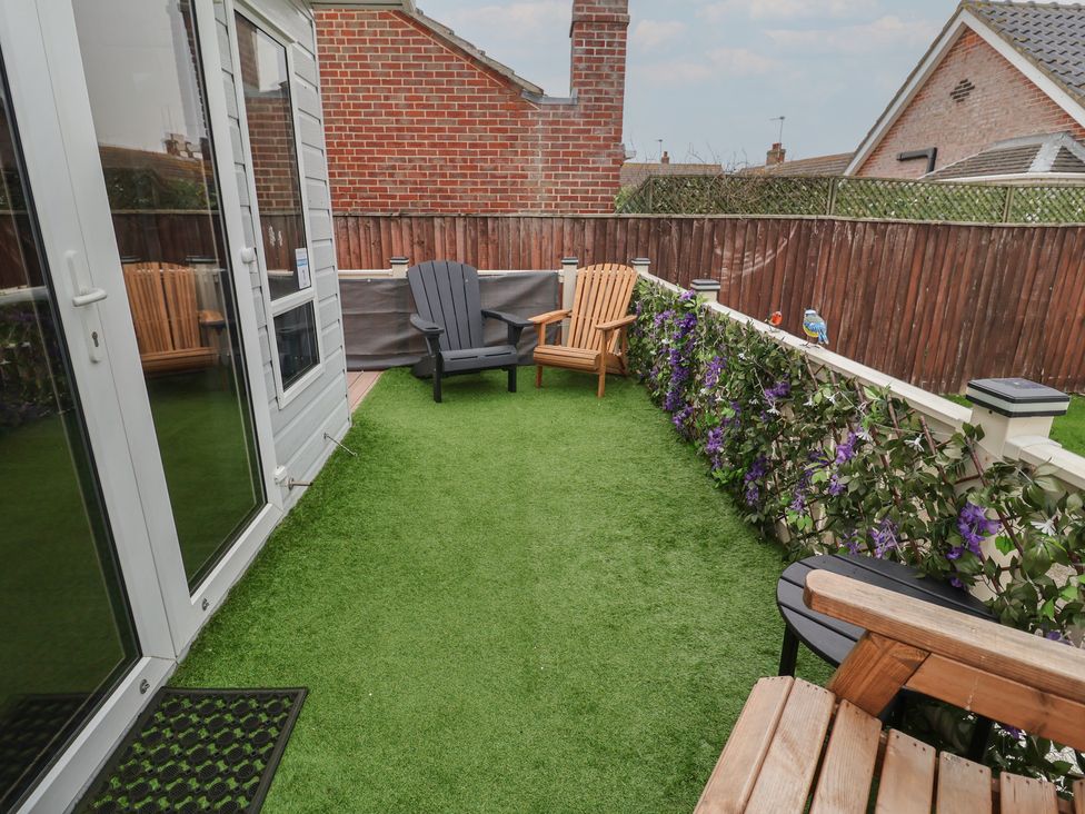 A garden with chairs and flowers at Offspray Court 1 Scratby