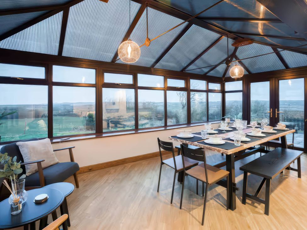 A dining table set with glassware in a conservatory at Kestrel Cottage Llangaffo