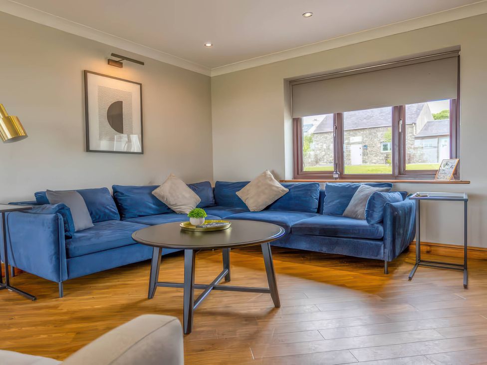 A living room with a blue sofa and coffee table at Kestrel Cottage Llangaffo