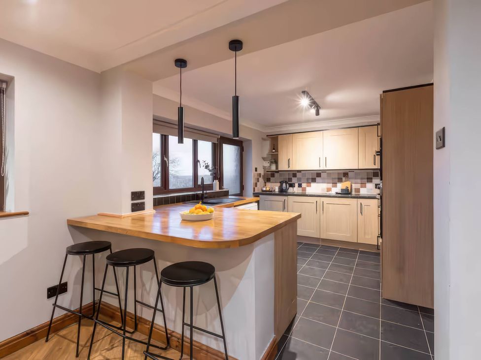 A kitchen with a bar area and appliances at Kestrel Cottage in Llangaffo