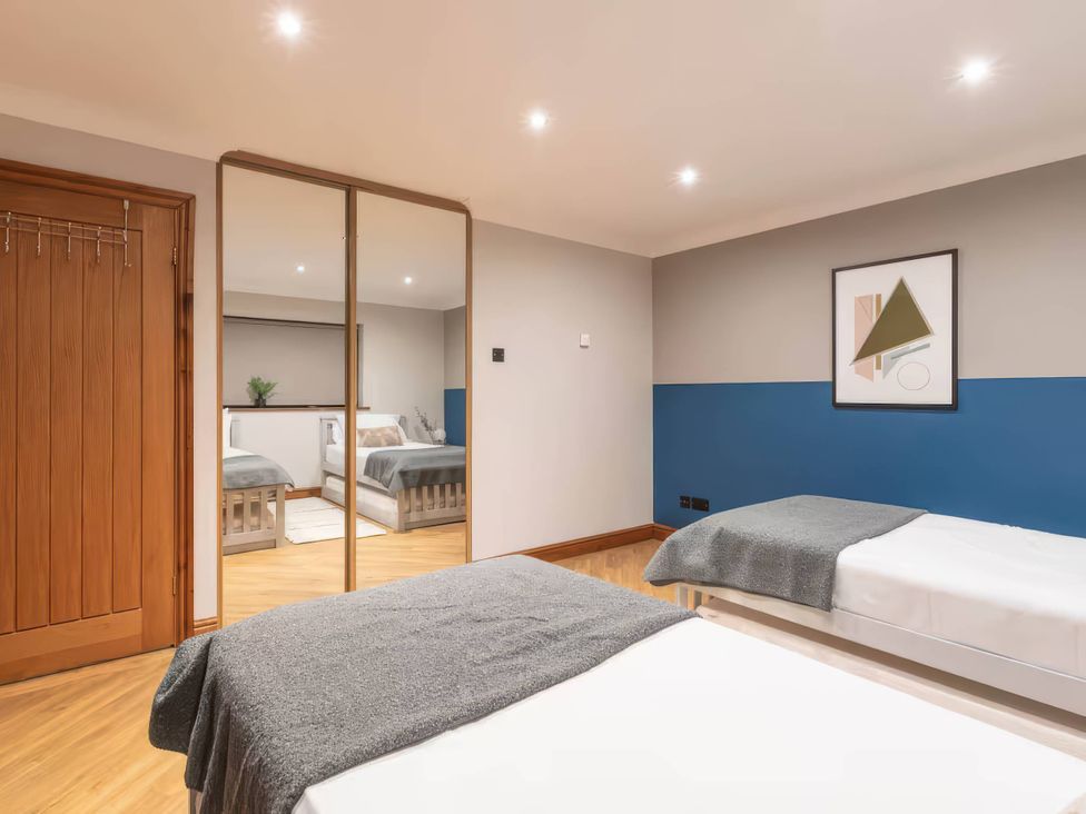 A bedroom with two beds and a mirror at Kestrel Cottage in Llangaffo