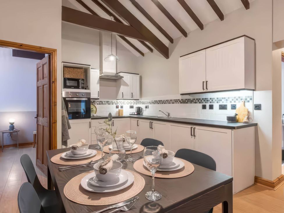 A kitchen with a dining table set at Swan Cottage, Llangaffo