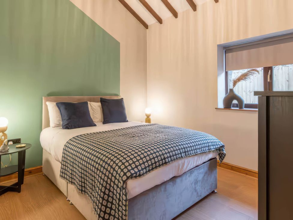 A bedroom with a bed and nightstand at Swan Cottage in Llangaffo