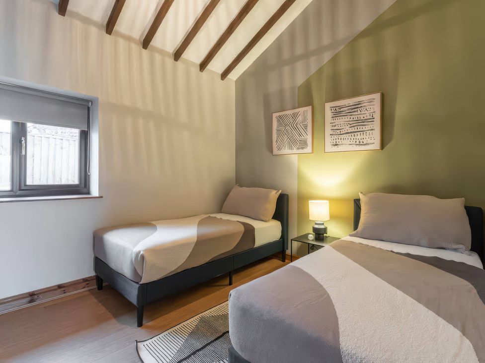 A bedroom with two beds and a window at Swan Cottage in Llangaffo
