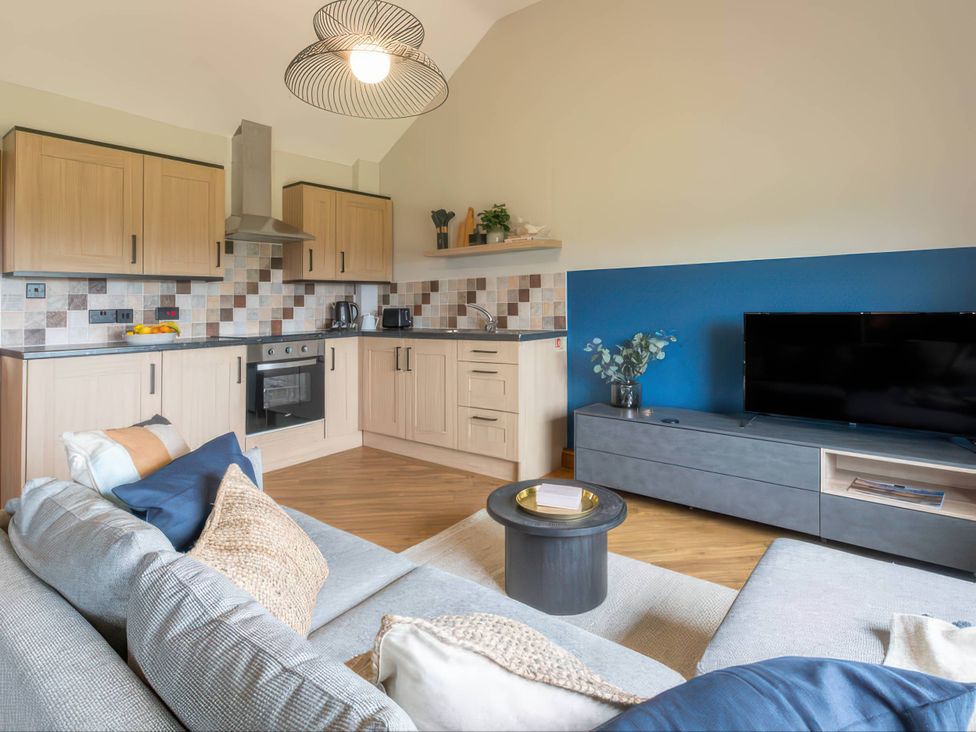 A kitchen with cabinets and a sofa at Wren Cottage in Llangaffo
