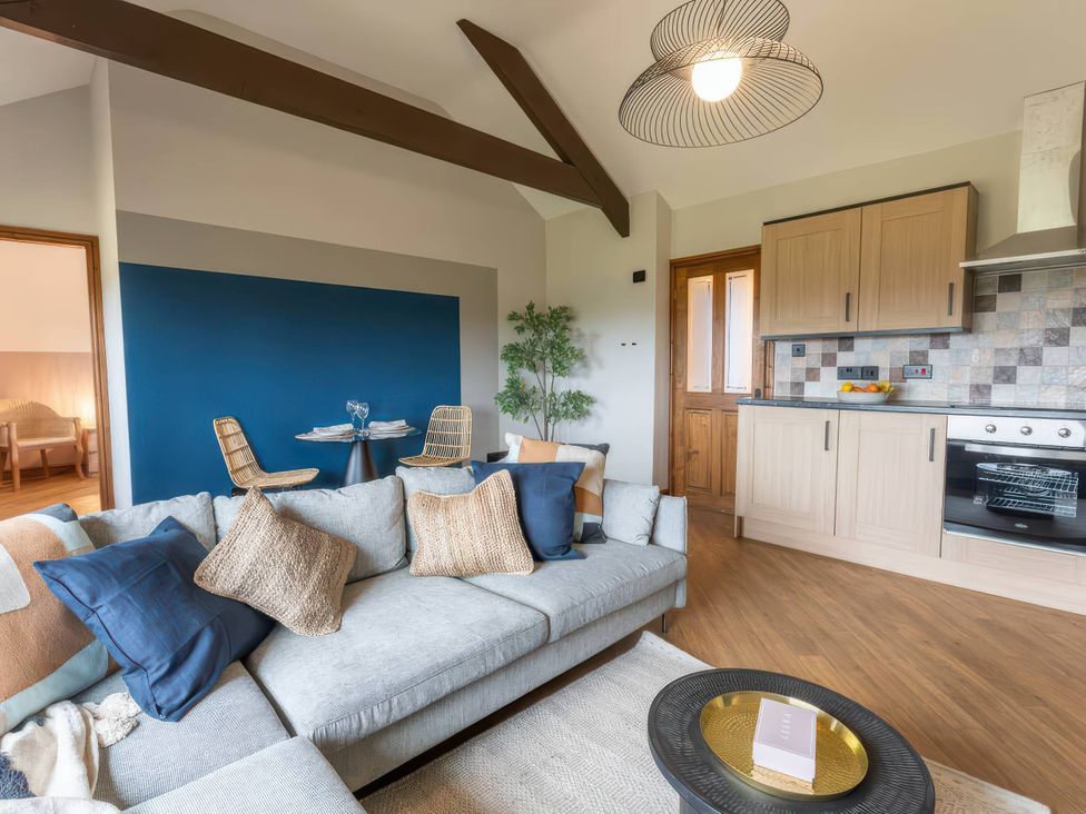 A living room with a sofa and kitchen area at Wren Cottage in Llangaffo