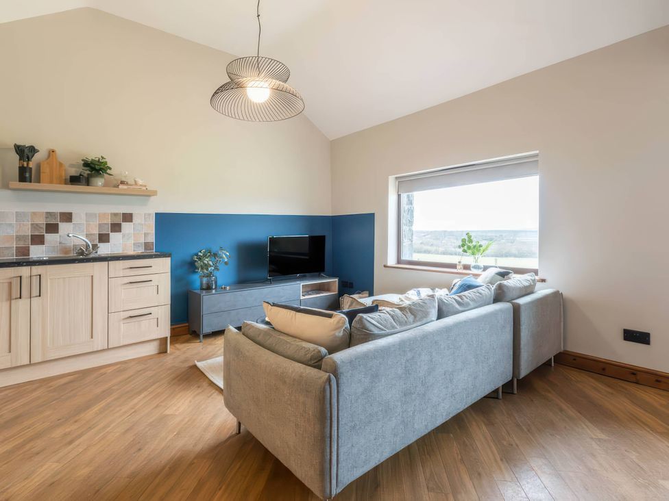 A living room with a sofa and television at Wren Cottage in Llangaffo