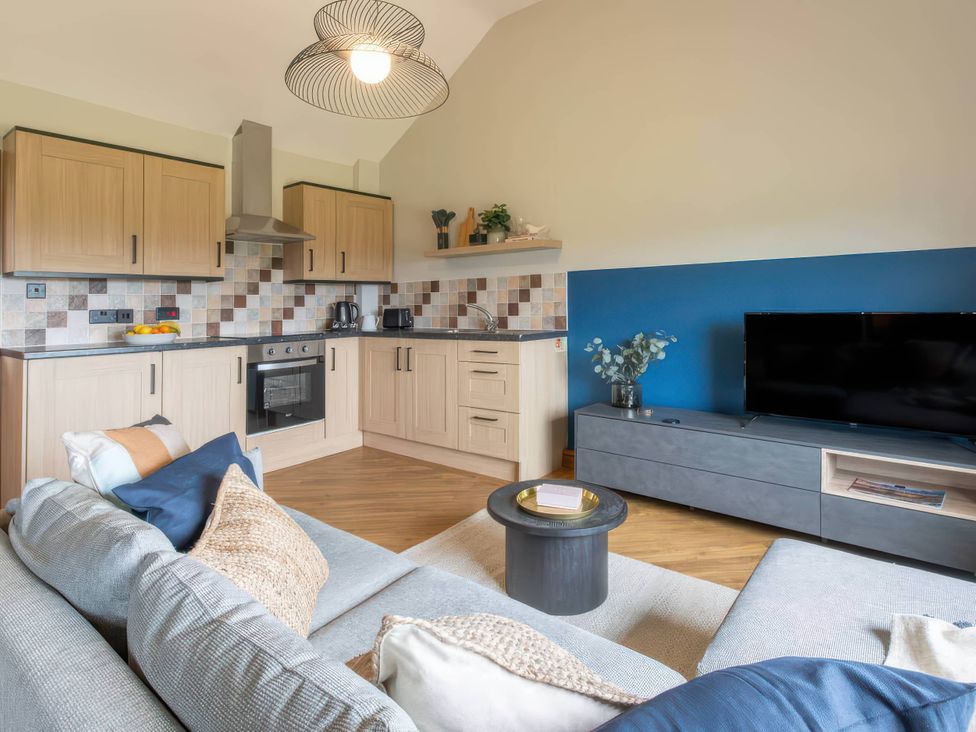 A kitchen with cabinets, stove, and a television at Wren Cottage in Llangaffo